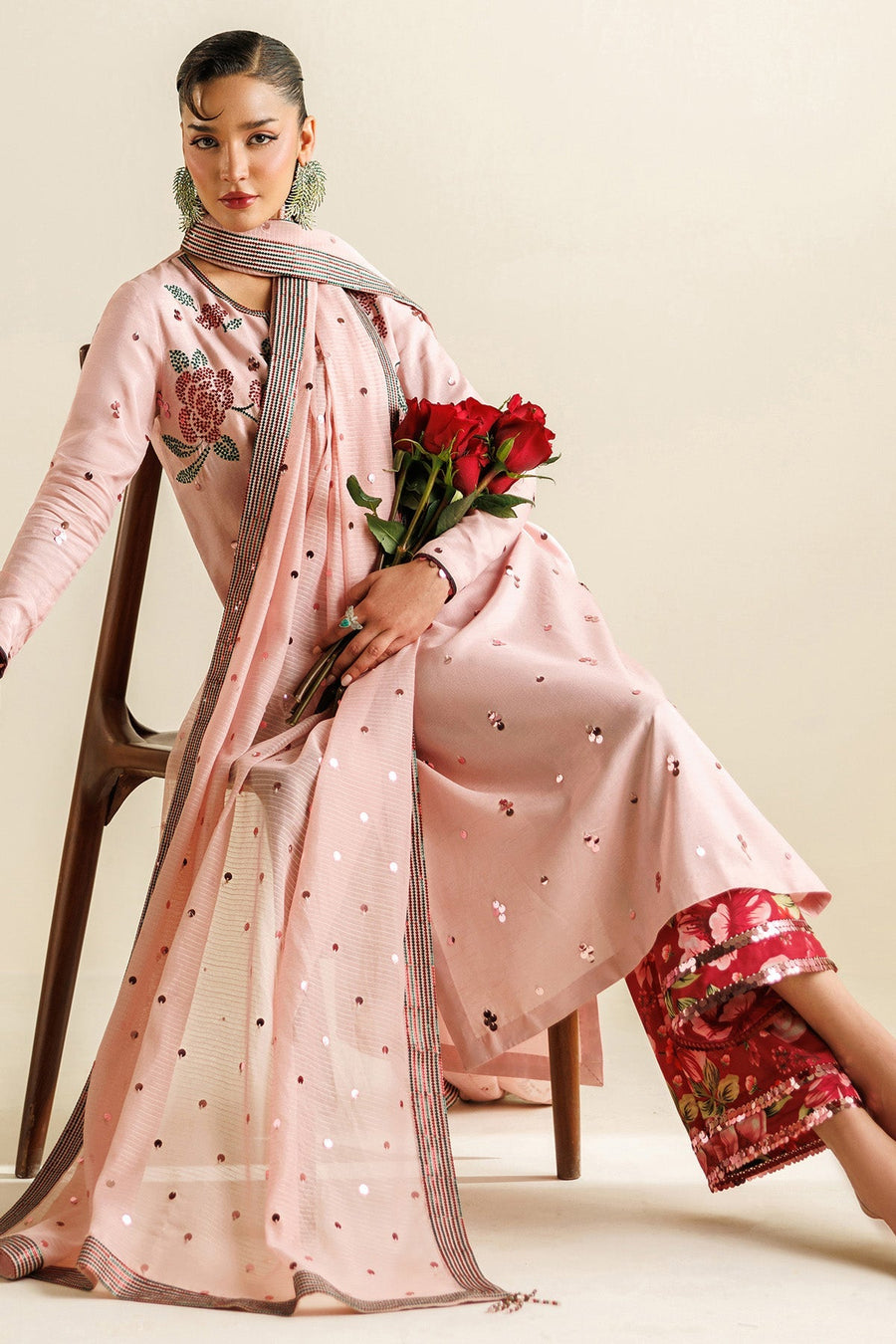 Close-up view of long sleeves and neckline embroidery detail on pastel pink unstitched suit fabric with sequin accents