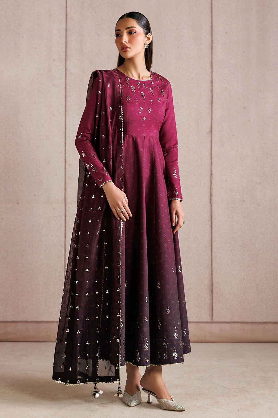 Woman posed holding a white decorative piece wearing elegant embroidered deep magenta Anarkali dress