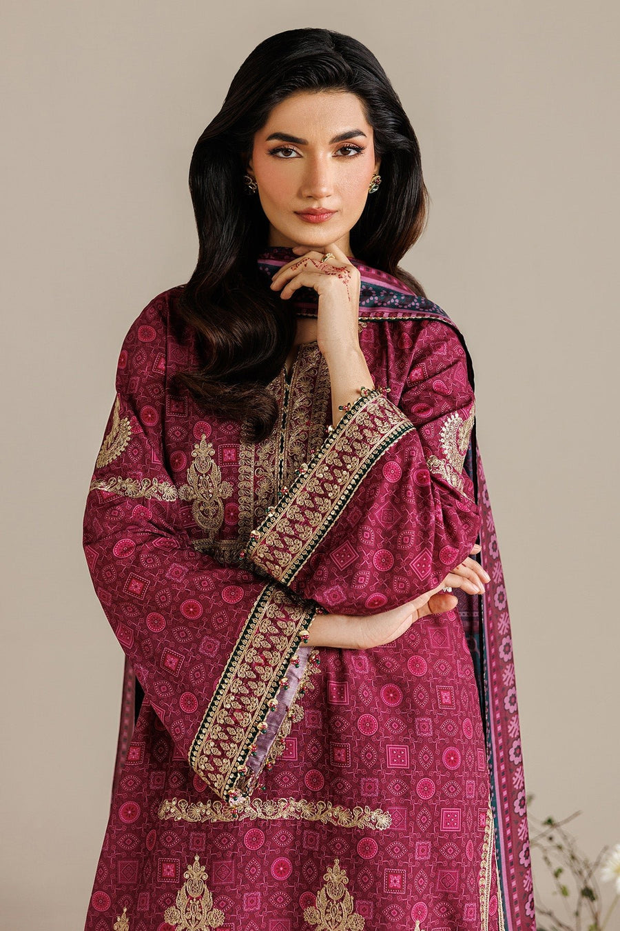 Close-up side view of model wearing embroidered deep magenta suit showing detailed embroidery on sleeve borders and intricate dupatta print.