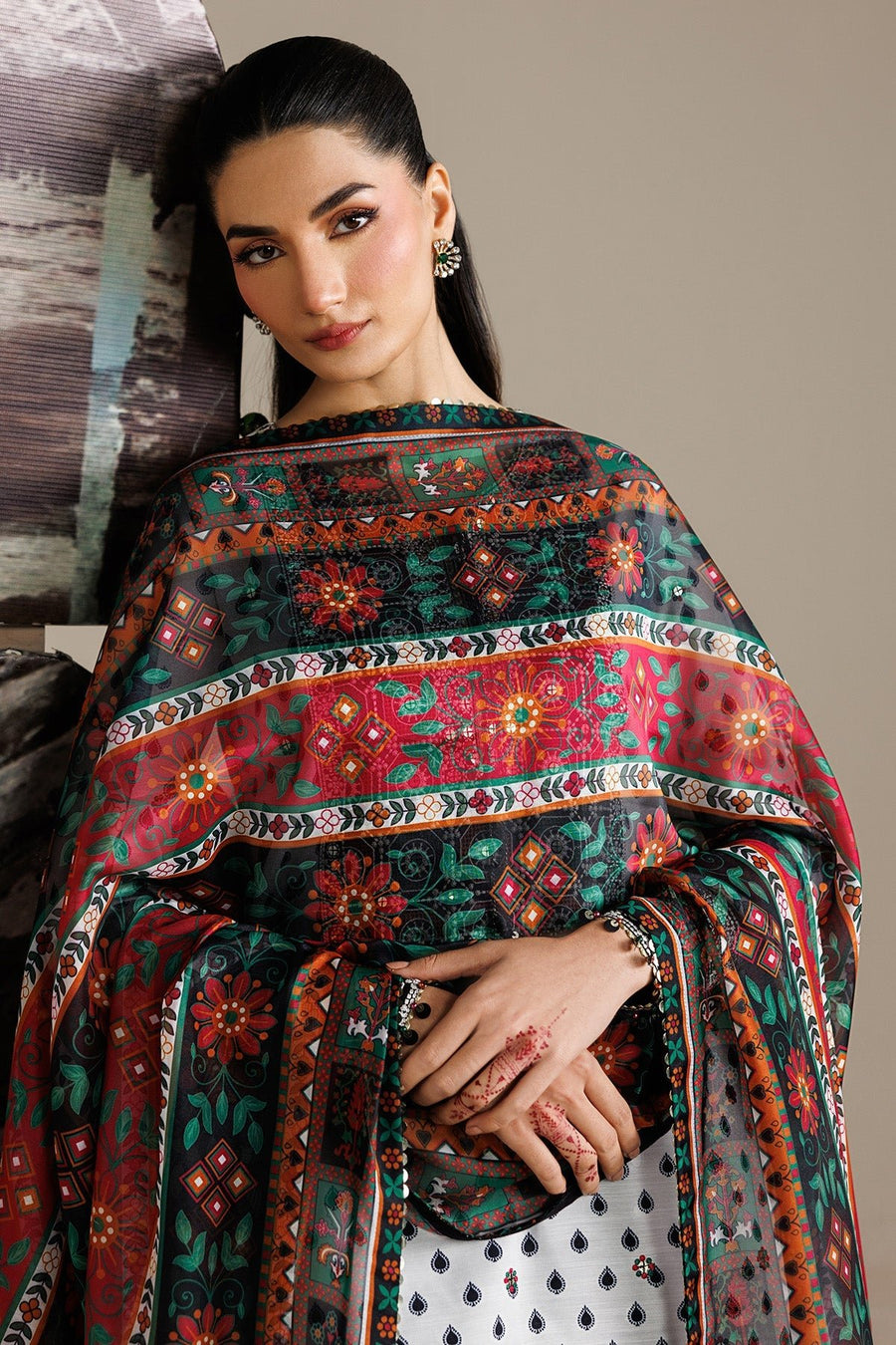 Front view of woman wearing white embroidered lawn suit with detailed neckline embroidery, paired with black printed trousers and ornate dupatta.