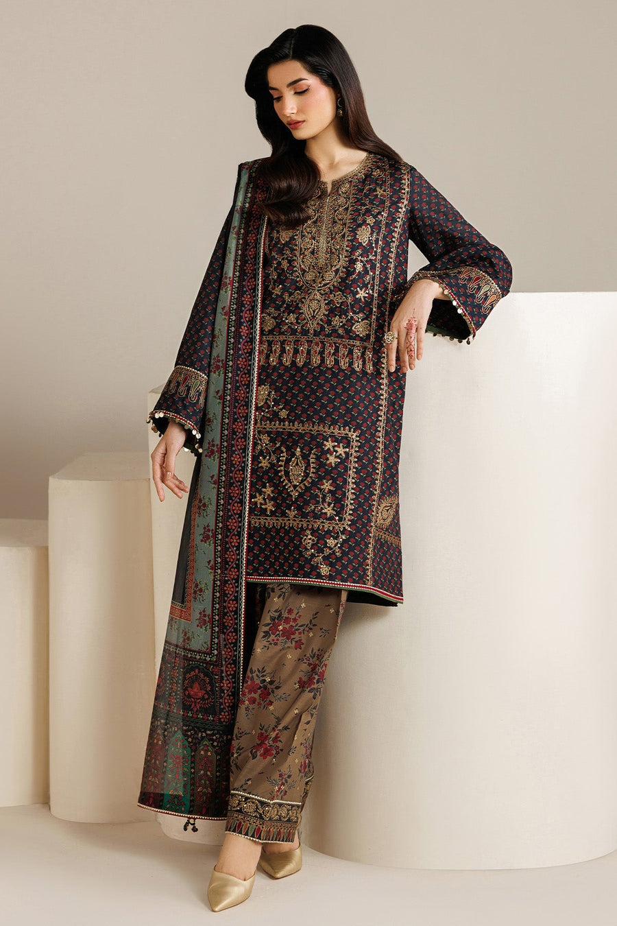 Woman wearing elegant navy blue embroidered shirt with floral printed trousers and sheer dupatta, posed standing