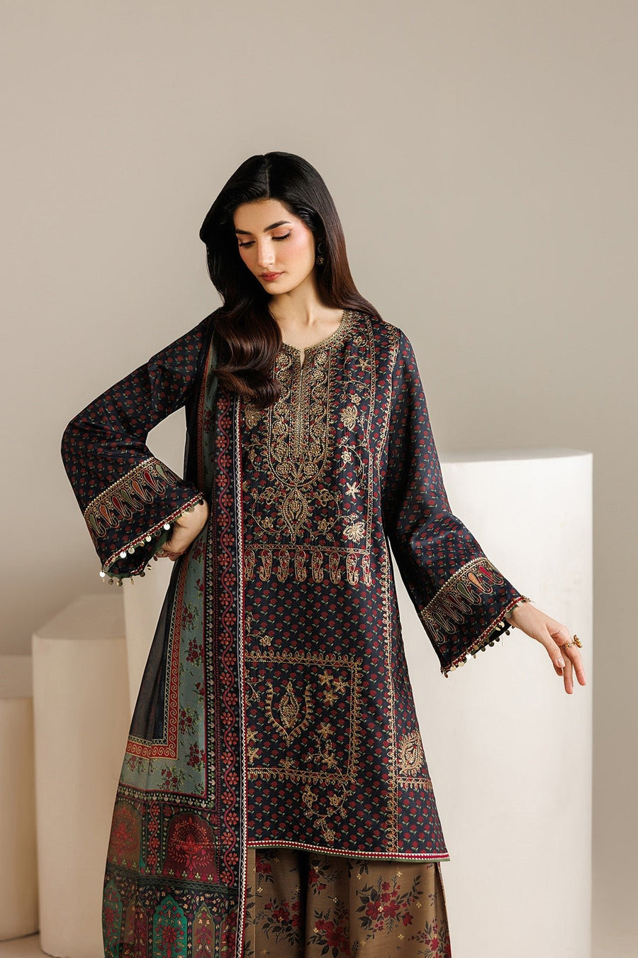 Model posing seated with navy embroidered shirt and floral pants, showing elegant festive wear look