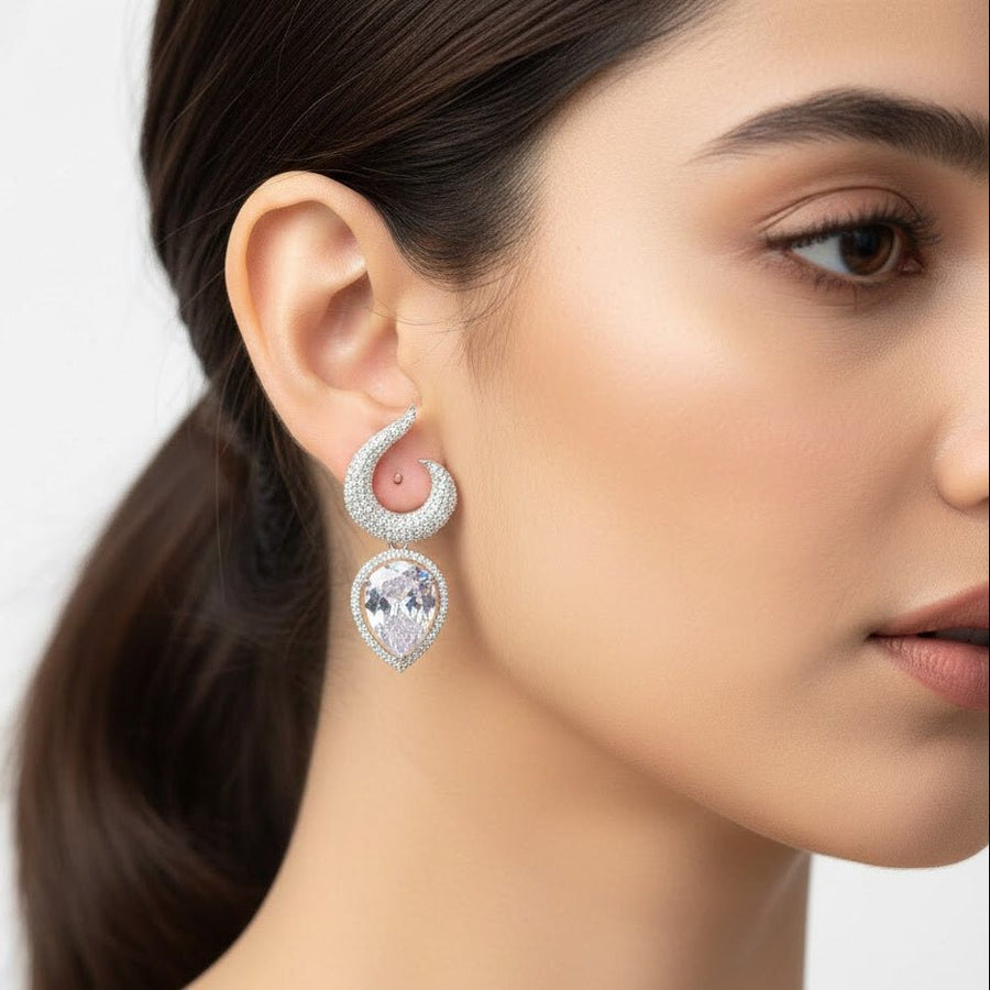 Close-up portrait of woman wearing gold-plated earrings with clear teardrop gemstones