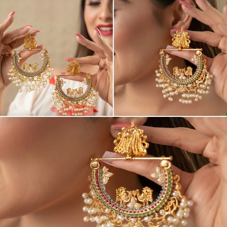 Woman holding intricate gold-plated pearl jhumka earrings with red and green stones