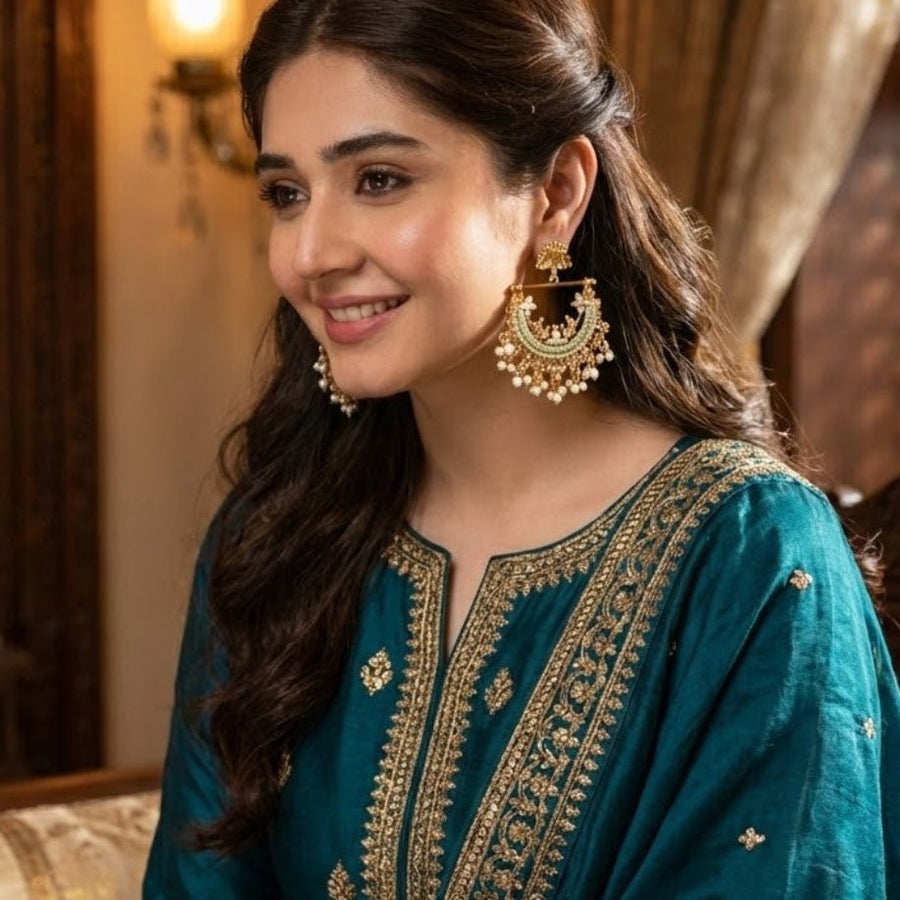 Woman smiling and wearing mint green stone gold-plated pearl jhumka earrings