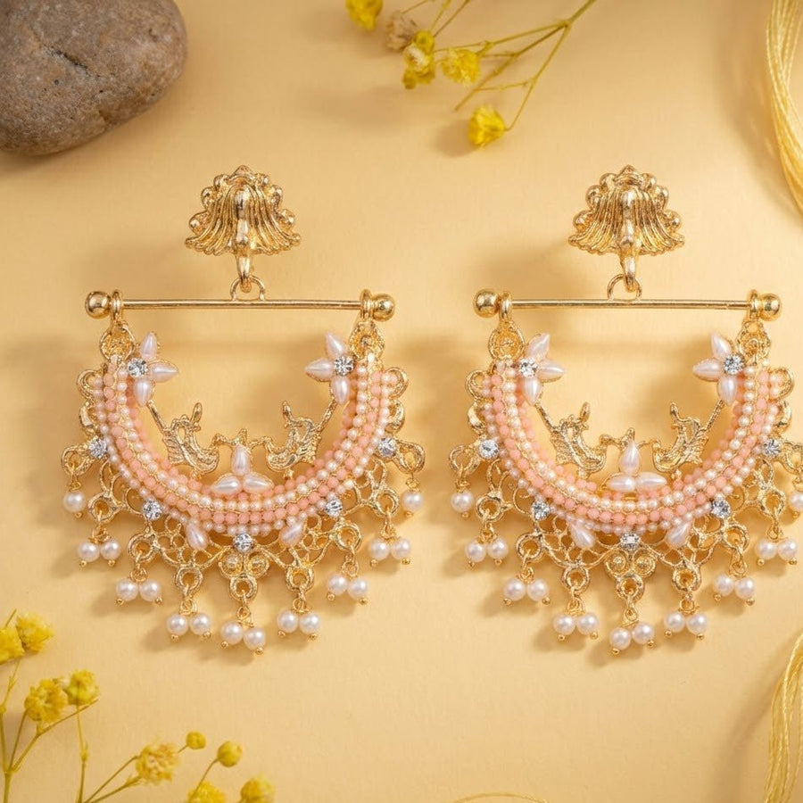 Gold-plated jhumka earrings with mint green stones and pearl drops displayed with yellow flowers