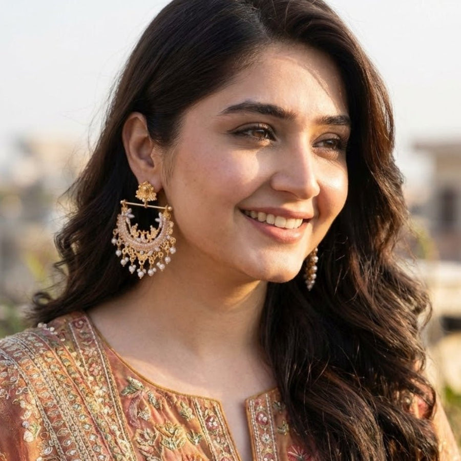 Woman smiling wearing peach stone gold-plated pearl jhumkas with matching outfit
