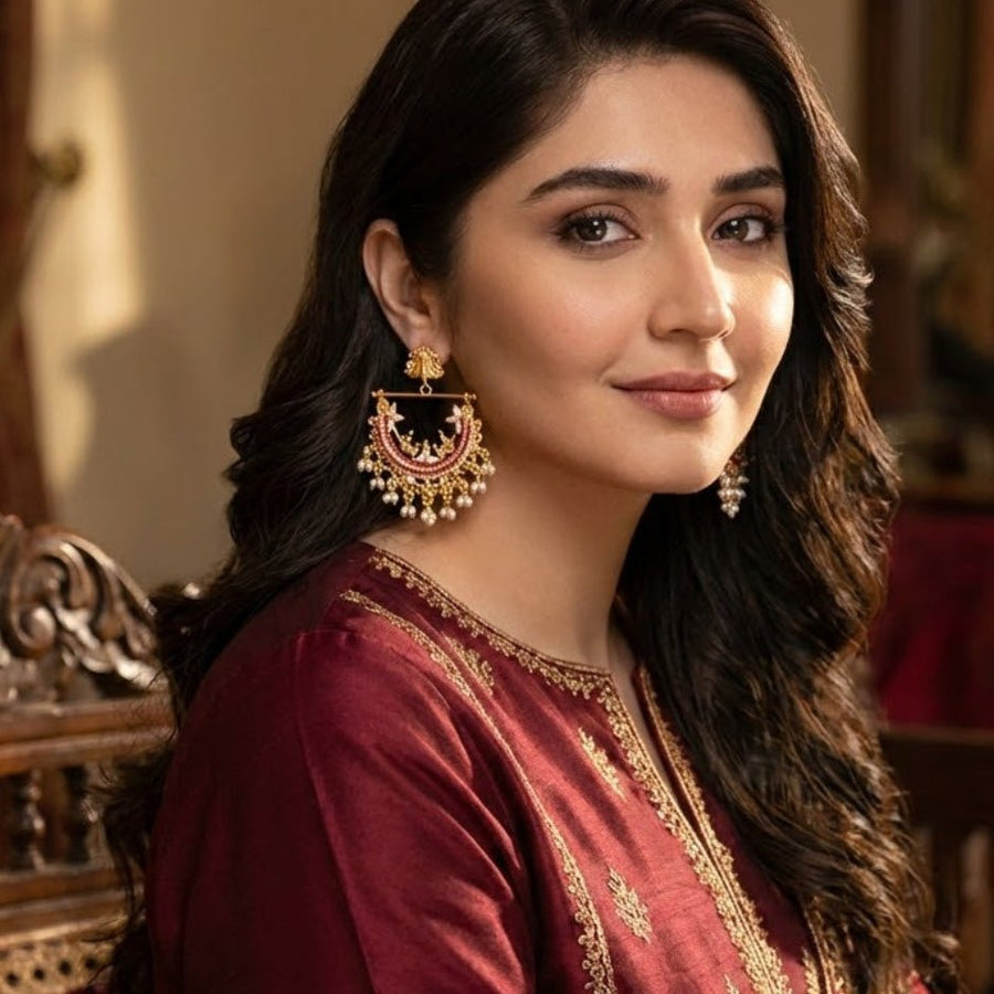 Woman wearing gold-plated pearl jhumka earrings paired with red traditional attire