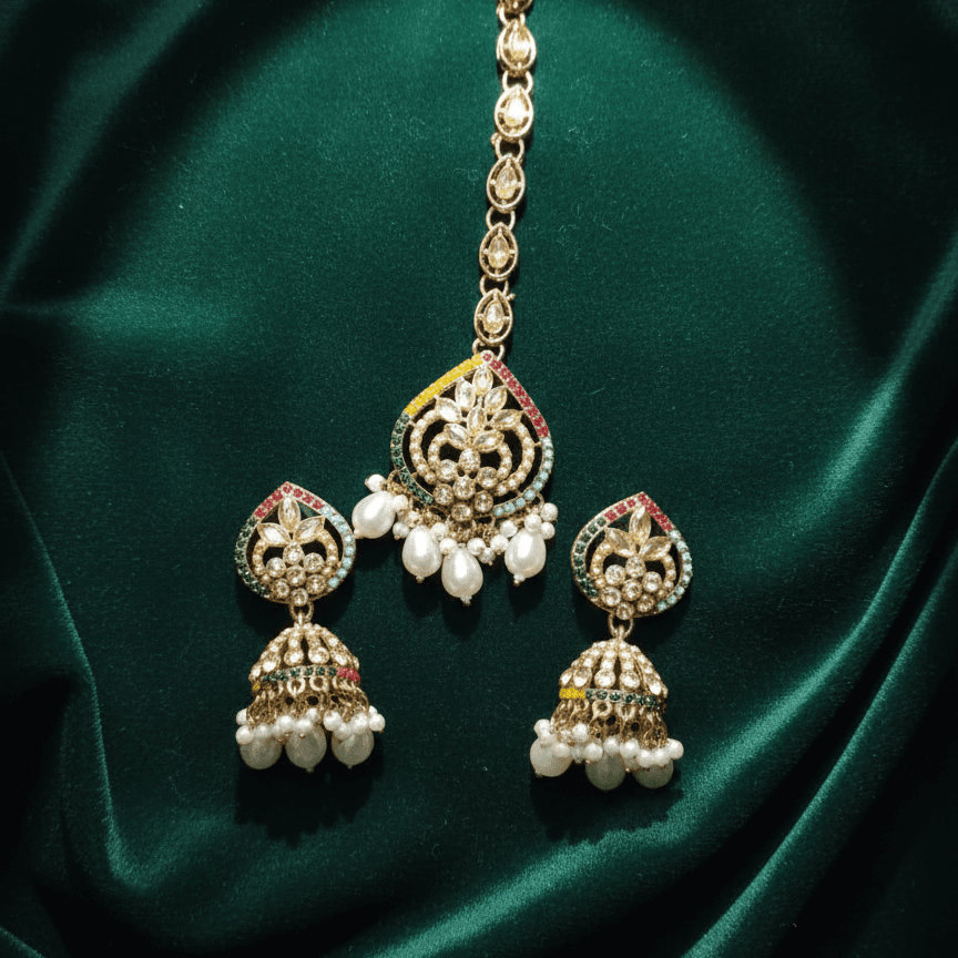 Majesty Pearl Drop earrings and maang tikka displayed on emerald green fabric background