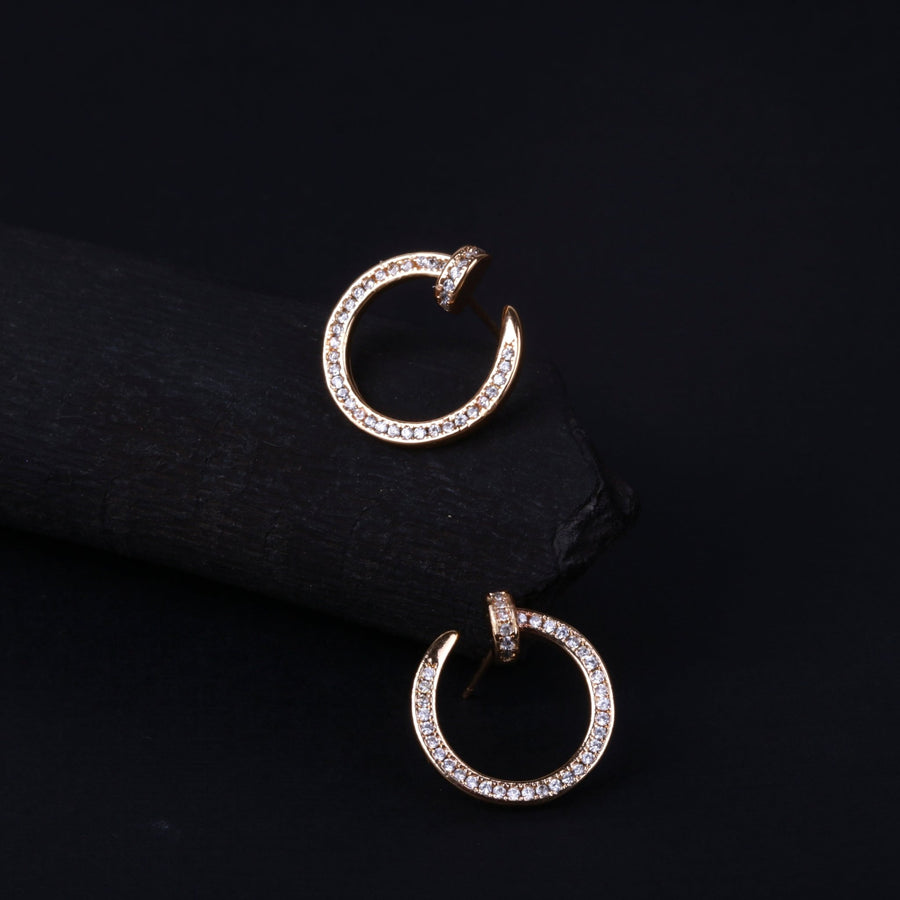 Close-up image of gold-tone open circle hoop earrings adorned with sparkling rhinestones on black background