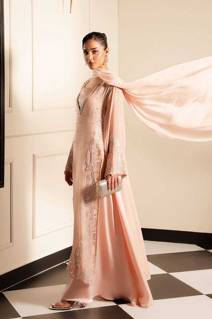 Side view of model wearing flowing layered blush pink dress with chiffon dupatta gracefully blowing in the air