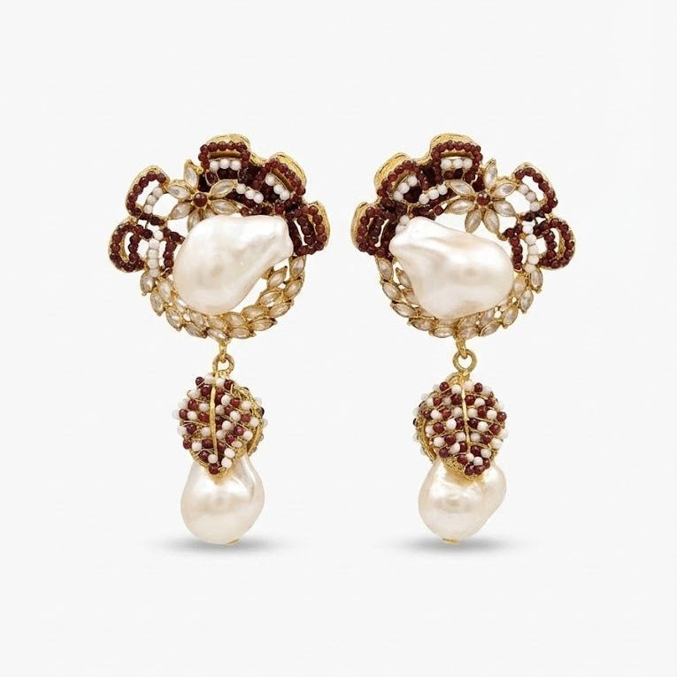 Pair of ruby red stone detailed drop earrings with white pearls against white background