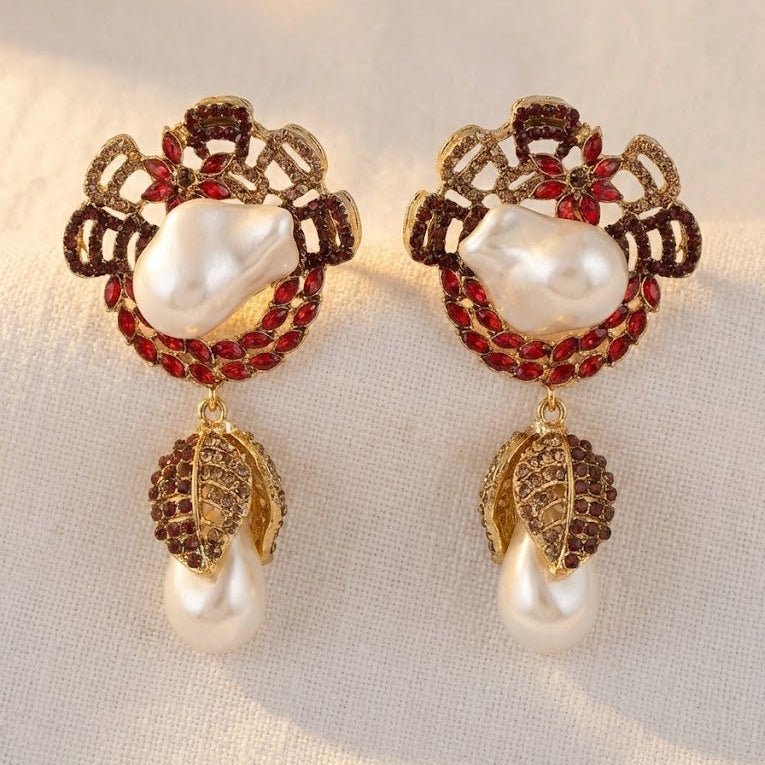 Ruby red stone drop earrings with white pearls displayed on light fabric background