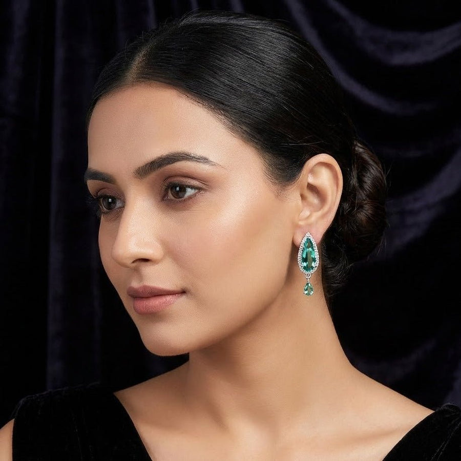 Model wearing green teardrop crystal earrings styled with a black velvet top and slicked back hair