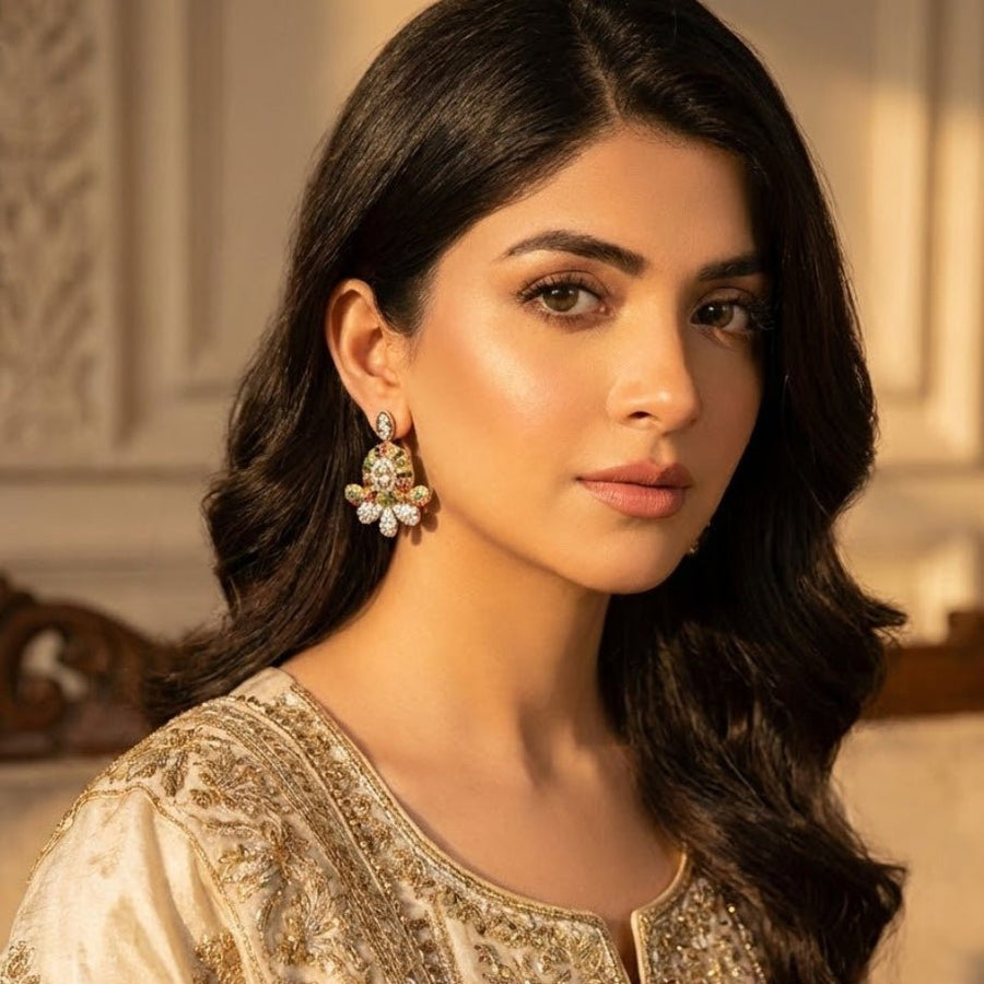 Model with soft smile wearing ruby red floral gemstone stud earrings and beige embellished outfit