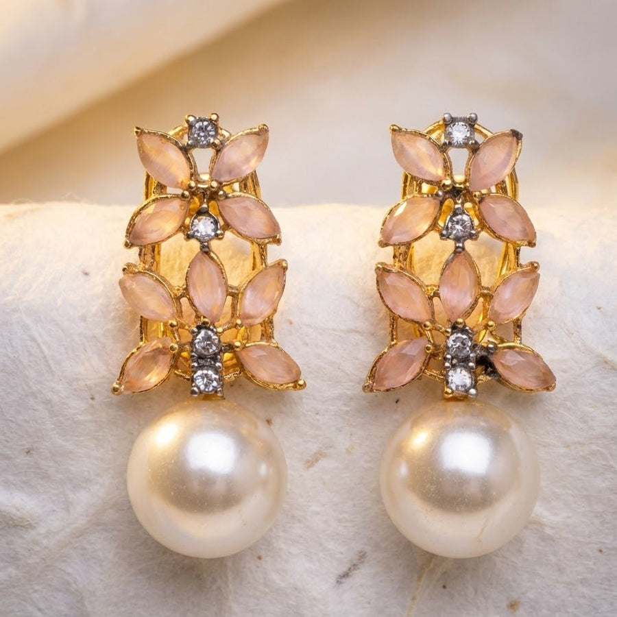 Close-up of gold-tone earrings with multicolor stones and pearl drops held in hand under sunlight