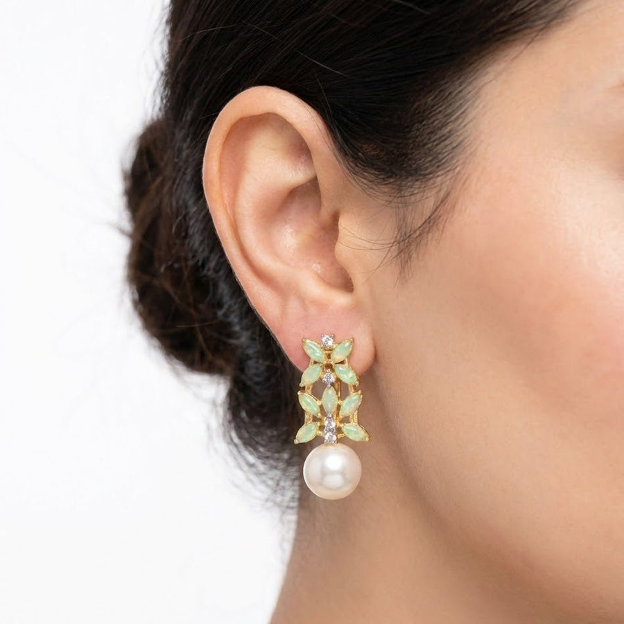Pearl drop earrings with textured black wood background highlighting colorful stones