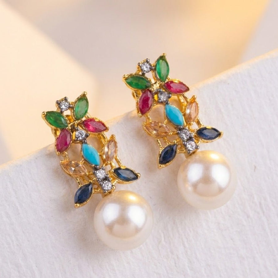Multicolor pearl drop earrings placed on light white textured surface with subtle shadows