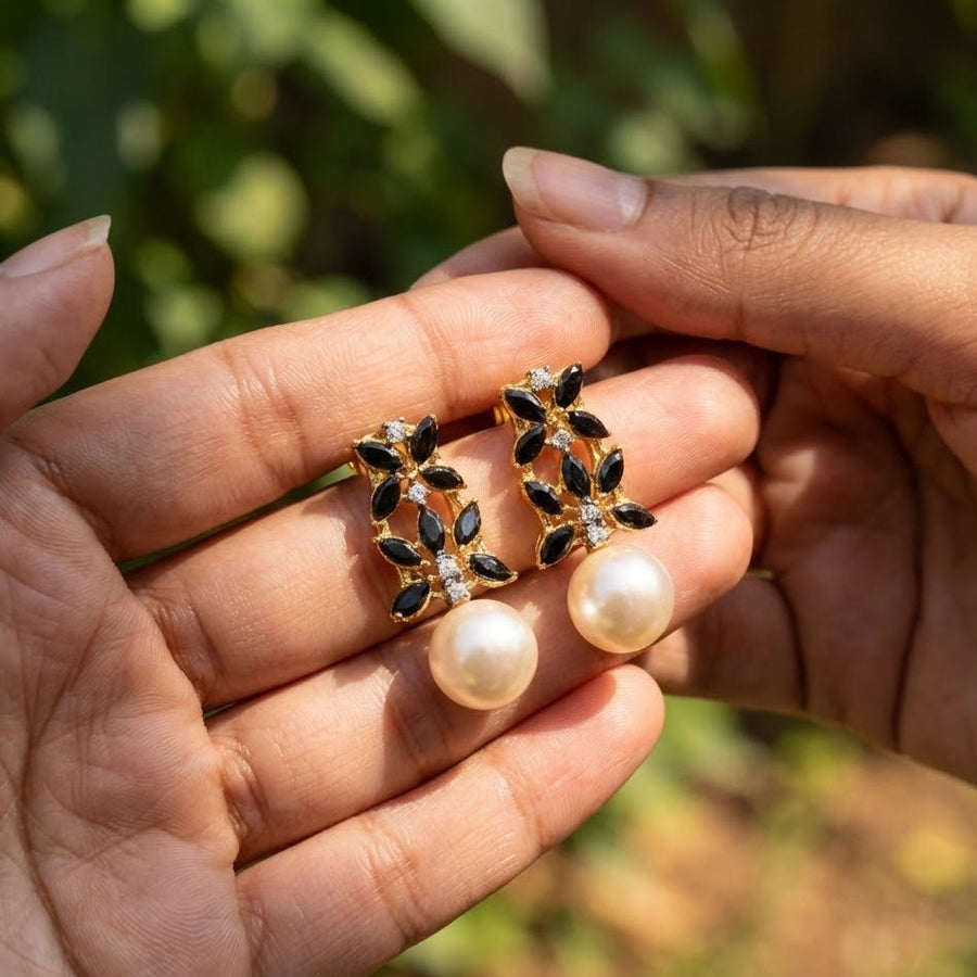 Hand holding black stone pearl drop earrings with clear close-up view