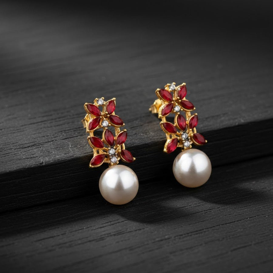 Red stone and pearl multicolor drop earrings on black wood textured surface