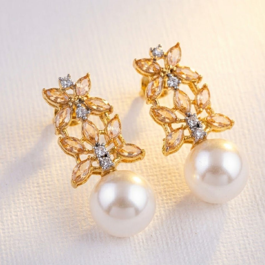 Pink stone and pearl drop earrings on smooth light surface with warm sunlight