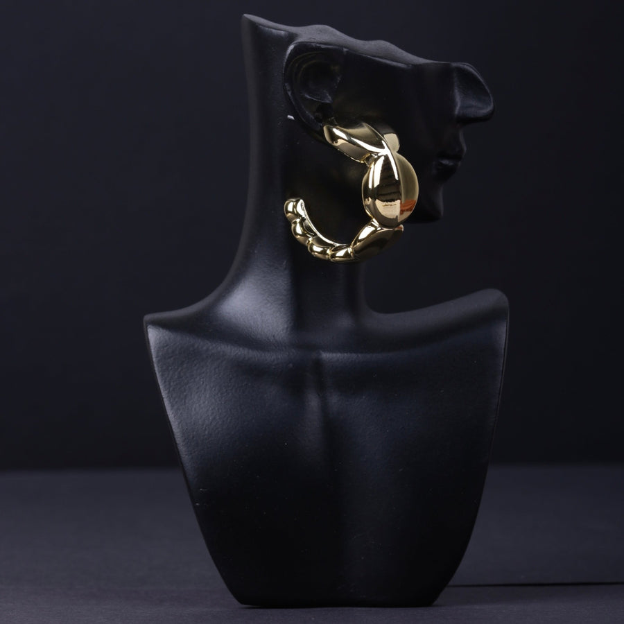 Gold chunky hoop earring displayed on black mannequin bust showing its sculptural design
