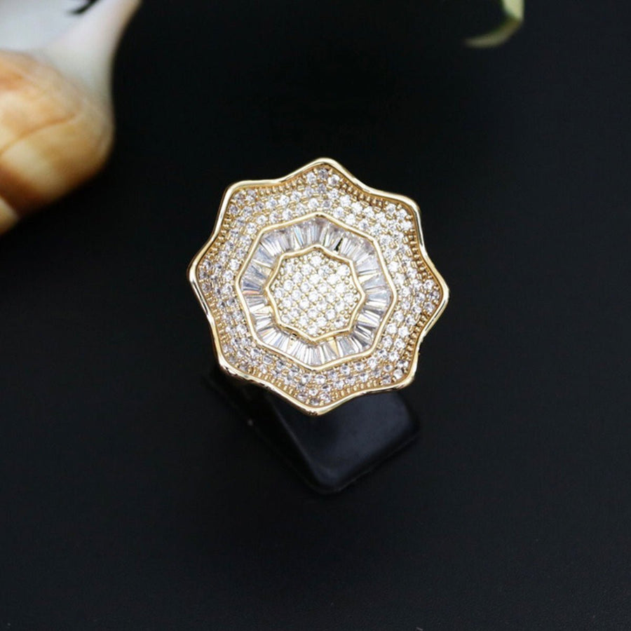 Gold-plated flower-shaped statement ring adorned with sparkling zirconia stones displayed on a black stand.