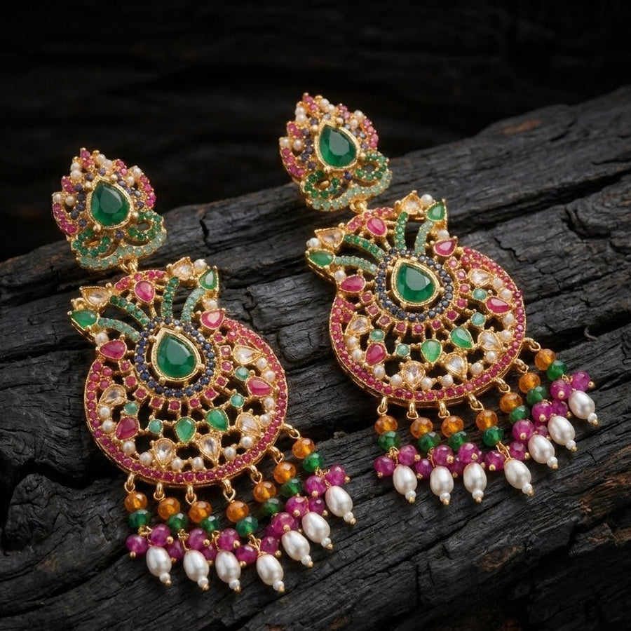 Pair of multi-gemstone jhumka earrings displayed on rustic black charred wood surface highlighting intricate colorful stones and pearl dangles