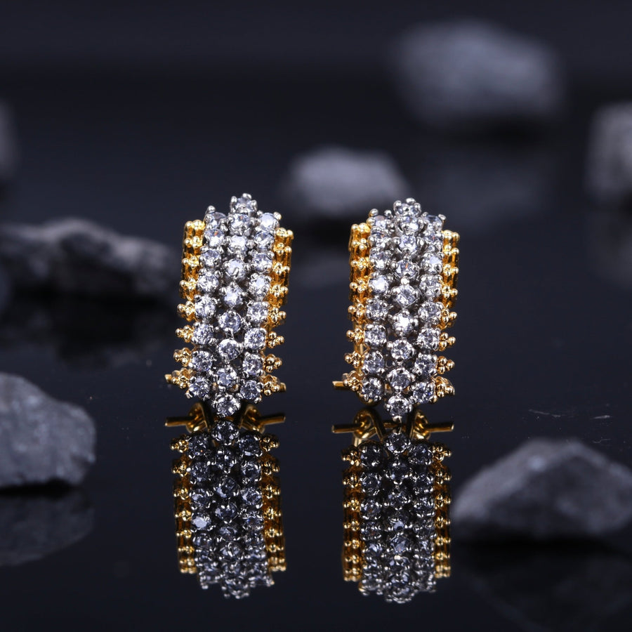 Close-up view of a pair of gold-plated stud earrings adorned with multiple rows of sparkling American zirconia stones on a reflective black surface with dark stones in background