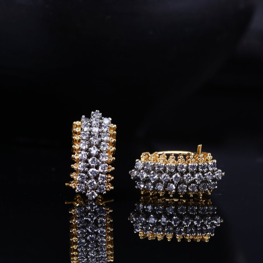Top angle of the gold-plated stud earrings revealing the detailed arrangement of American zirconia stones and the clasp mechanism on a reflective dark surface
