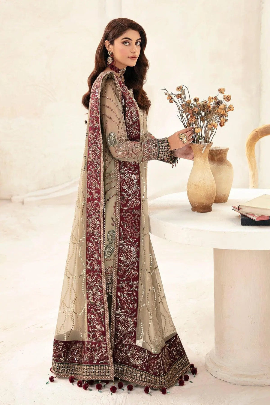 Seated woman showcasing full embroidery and maroon bordered chiffon dupatta draped over suit