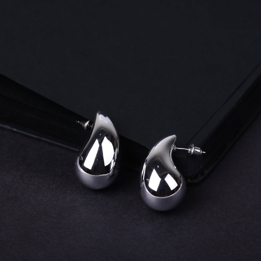 Silver-toned polished teardrop stud earrings with smooth reflective surface on black background