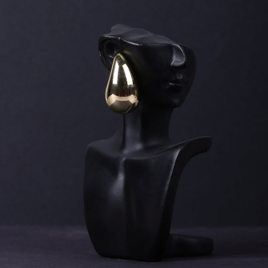 Gold-toned polished teardrop stud earring displayed on a black sculptural bust showcasing elegant style