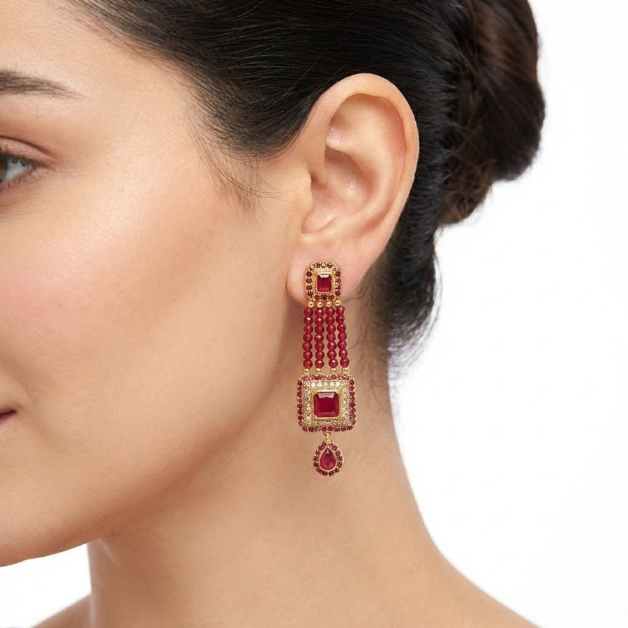 Red gemstone bead earrings on black display stand with black stones background