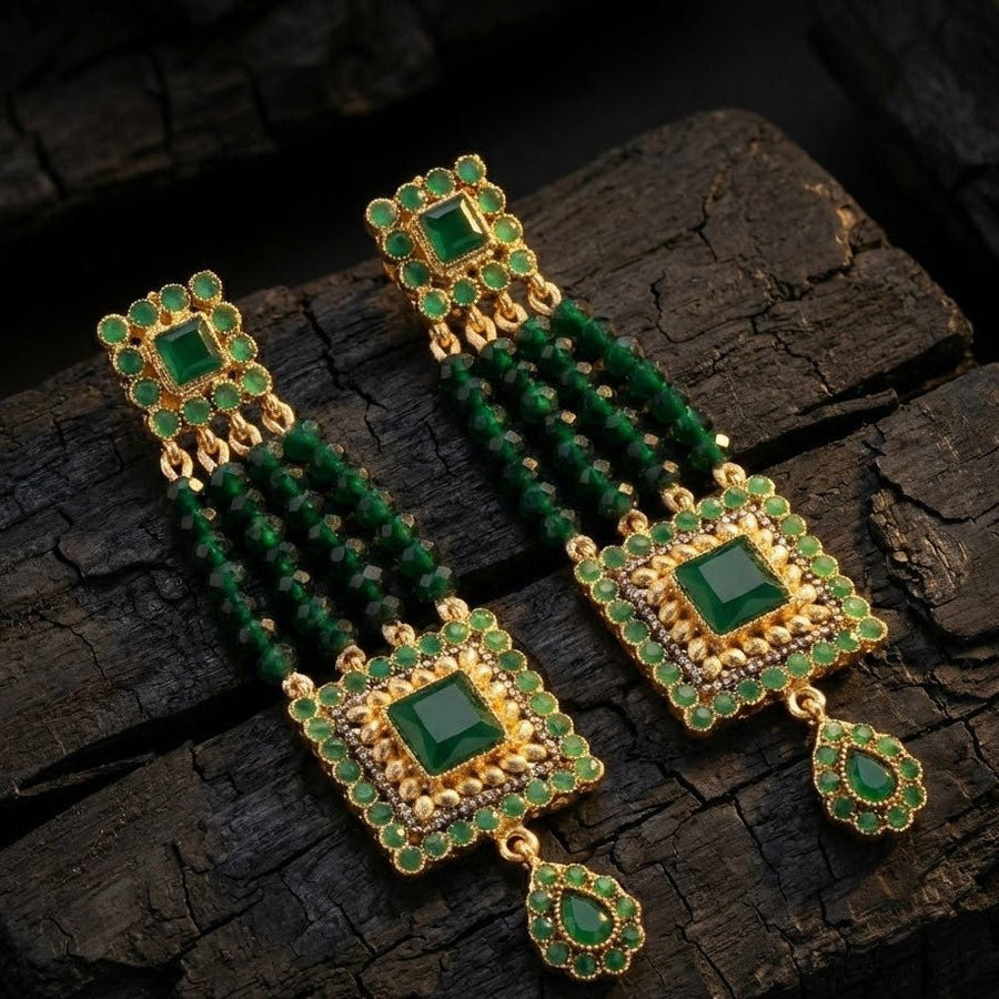 Green gemstone bead earrings displayed on pale stone with warm natural light