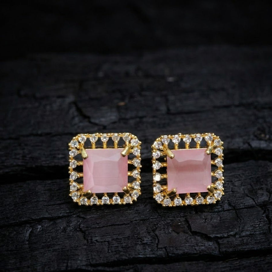 Pink halo stud earrings displayed on light yellow surface with yellow flowers emphasizing soft color and sparkle