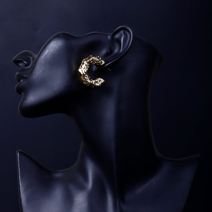 Detailed view of gold textured hoop earring on black display mannequin