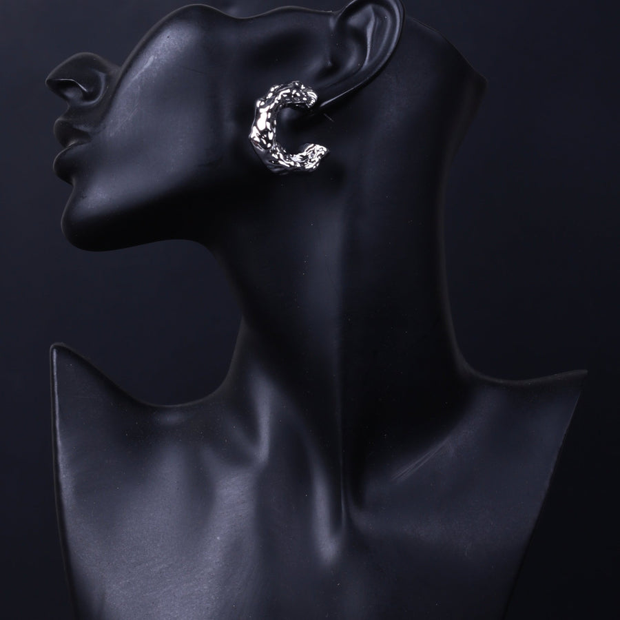 Silver textured hoop earring worn on black display mannequin profile