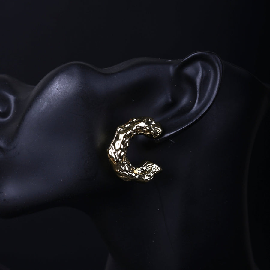 Close-up of gold textured hoop earring worn on black mannequin ear