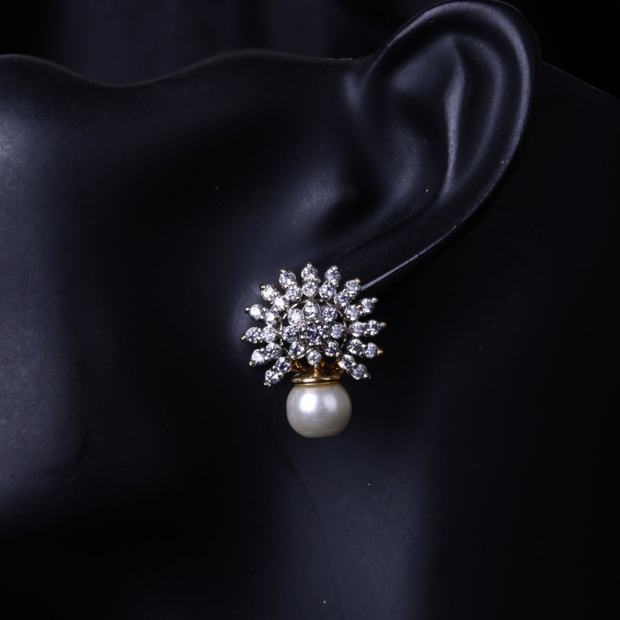 Close-up of pearl drop earrings with floral crystal design on black mannequin