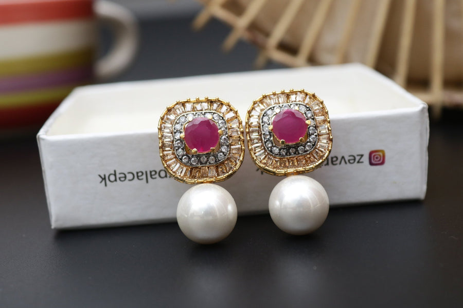 Pair of gold-tone earrings featuring red central stones with surrounding crystals and large pearl drops