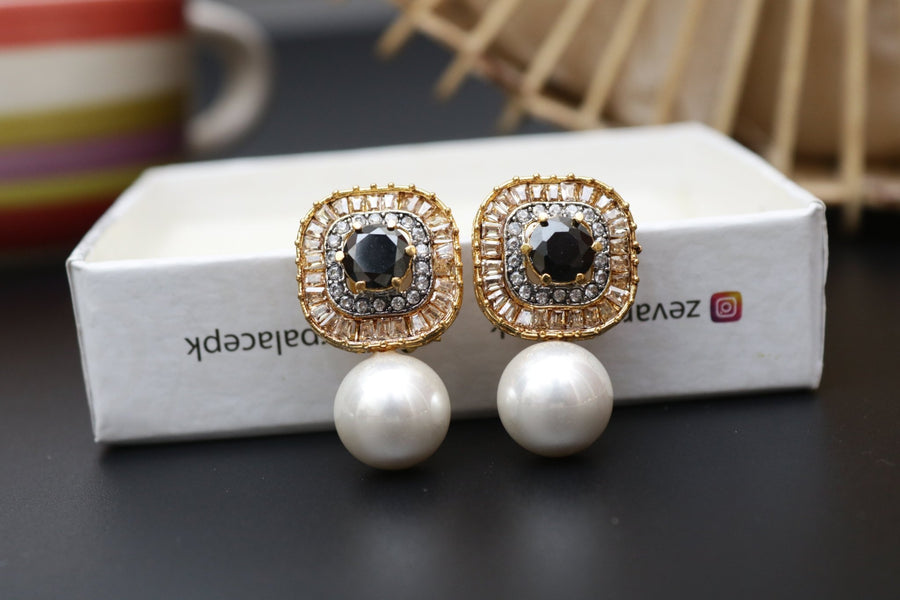 Pair of gold-tone earrings with black central stones encircled by crystals and large pearl drops