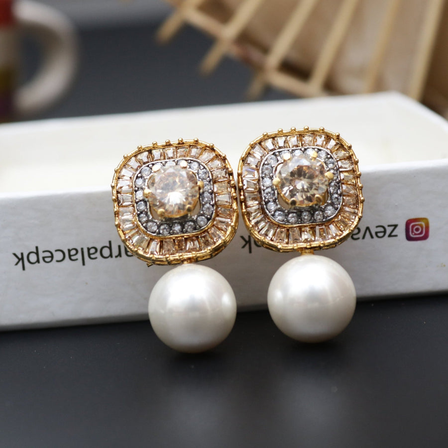 Pair of gold-tone earrings featuring clear central stones surrounded by small crystals and large pearl drops
