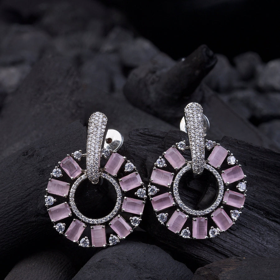 Elegant circle drop earrings with pink baguette and round stones held in hand outdoors