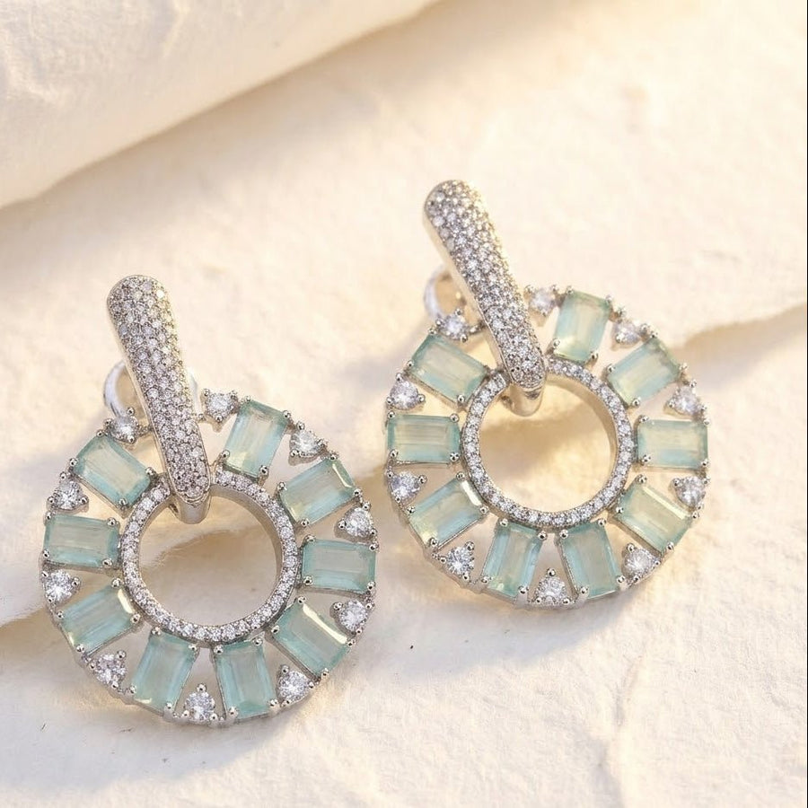 Elegant gold plated mint green stone circle drop earrings displayed on black textured surface