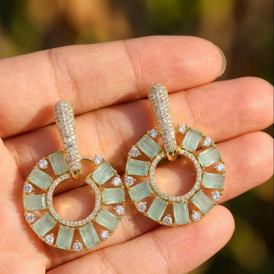 Model wearing gold plated mint green stone circle drop earrings with a soft smile