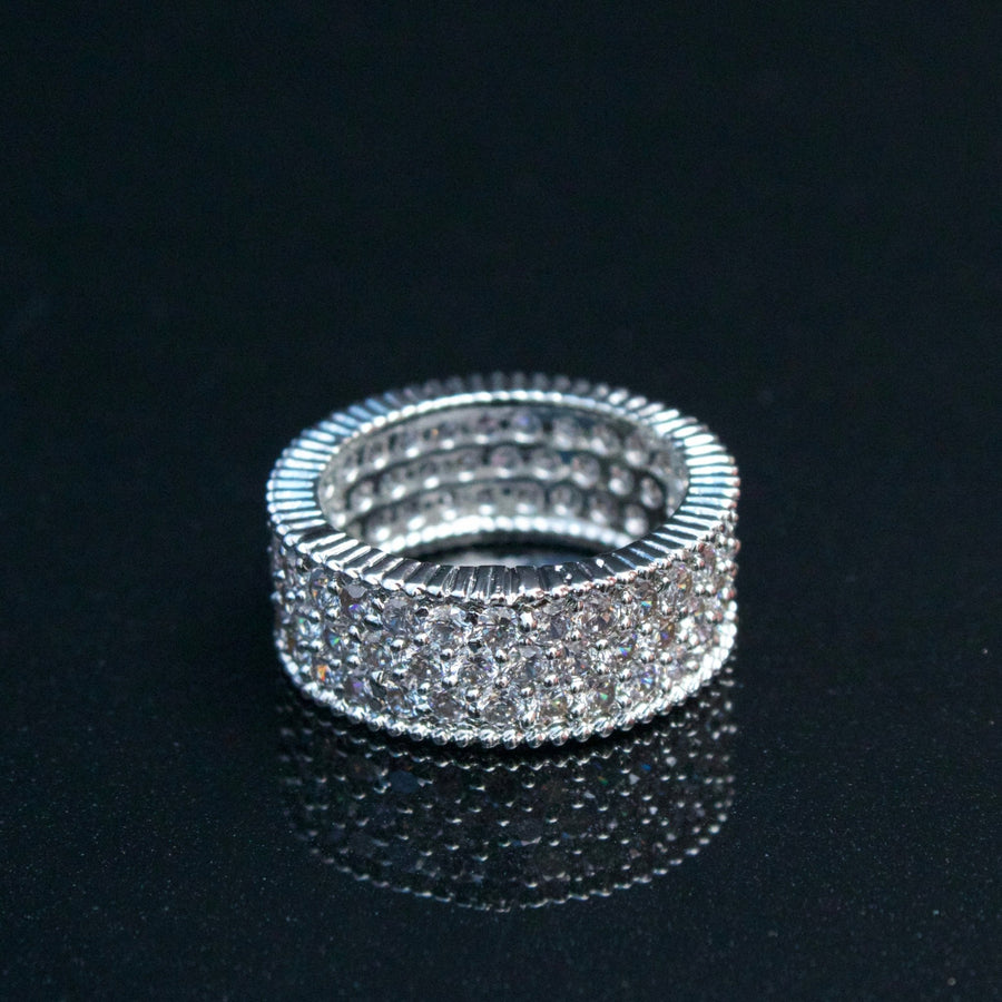 Silver-tone cubic zirconia band ring reflecting light on black surface